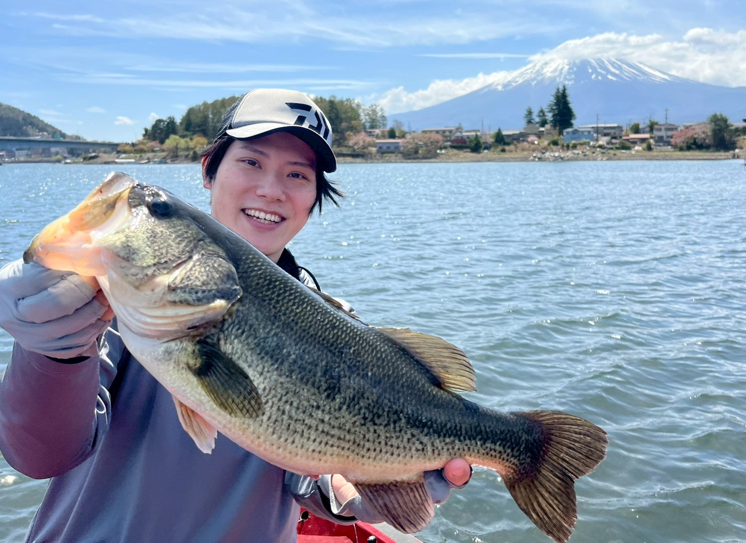 Smiling angler with a big largemouth bass and a clear view of Mt. Fuji on Lake Kawaguchi