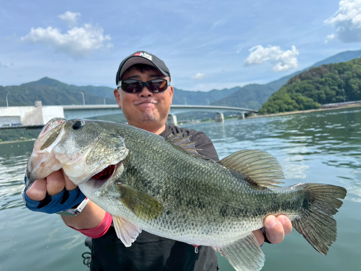 Angler holding a largemouth bass on Lake Kawaguchi on a sunny summer day